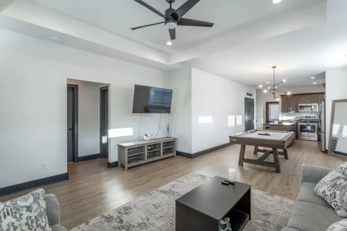 This image features a spacious, open-plan living area with a comfortable sofa, coffee table, television, and dining table set up for relaxation and socializing. The layout supports activities like watching movies, playing games, and hosting friends, while the décor feels contemporary and welcoming.