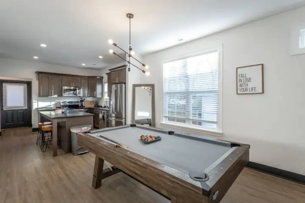 A bright, welcoming space that seamlessly blends the pool table area with the kitchen and large windows. The room feels open and vibrant, filled with natural light and inviting décor, ideal for both lively gatherings and casual afternoons.