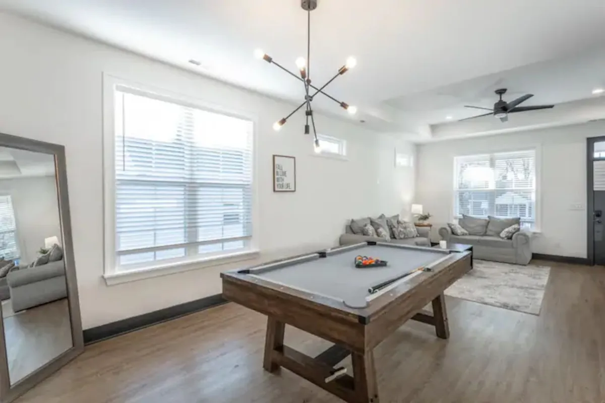 A casual game zone featuring a pool table, a comfy sofa for relaxing between games, striking lighting, and a mirror that enhances the sense of space. The atmosphere is lively yet cozy, ideal for friendly competition and laid-back evenings with family and friends.